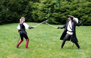 Deux escrimeurs se menacent à l'épée sur la pelouse