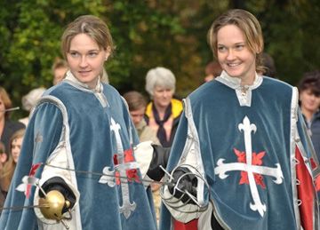 Deux femmes en capes bleues de mousquetaire, épée à la main